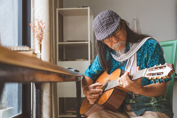 asian senior men enjoy playing guitar in living room at home - men artist guitarist guitar imagens e fotografias de stock