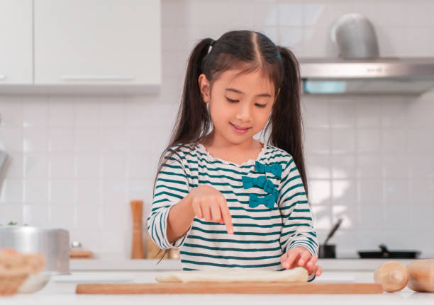 istock Asian girl having fun using finger to knead the dough and preparing bakery in the kitchen. 1287765569