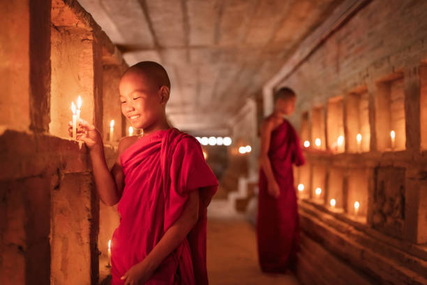 smiling burmese novice monks lighting candles in temple tomb bagan myanmar - novice buddhist monk imagens e fotografias de stock