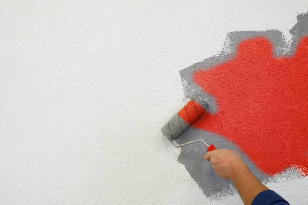istock painting walls with a roller in his left hand. 1287779681