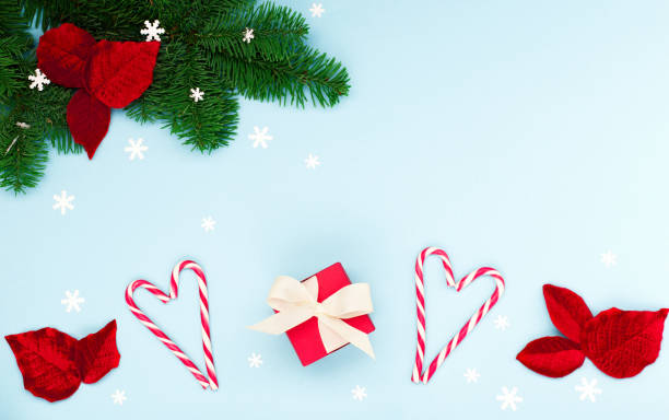 istock Christmas holiday card - Xmas tree branches, red gift box,  snowflakes, candy canes on pastel blue background. 1287782286