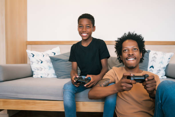 istock Father and son playing video games together at home. 1287786067