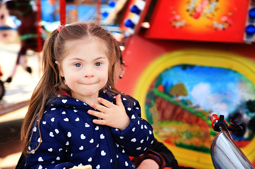 Little girl with down syndrome having fun in amusement park