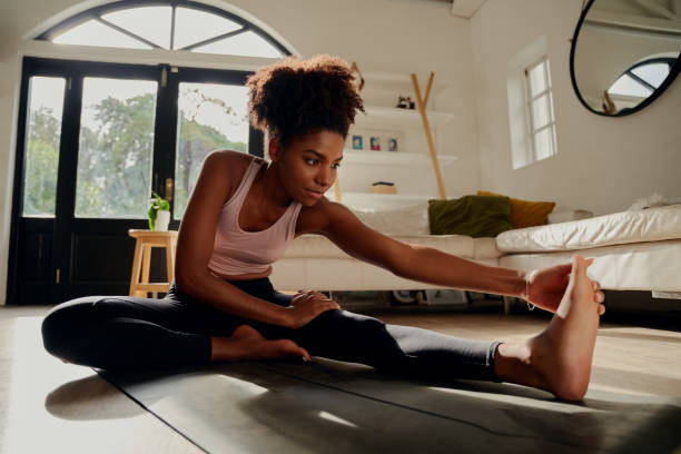 istock Slim sportswoman in sportswear warming-up muscles before workout doing stretching exercise sitting on floor at home 1287793636