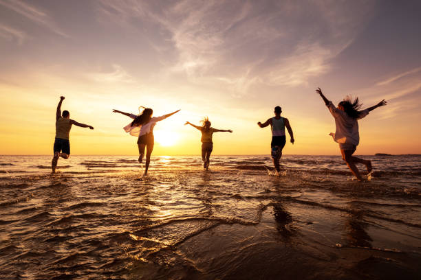 istock Five happy friends runs at sunset beach 1287803312
