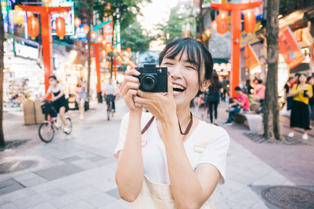 Portrait of Asian woman taking photos with a retro camera. She's looking excited.