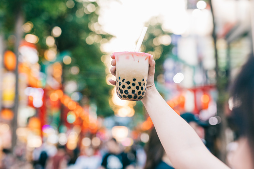 Hand holding bubble tea on the streets of Taipei. With copy space.