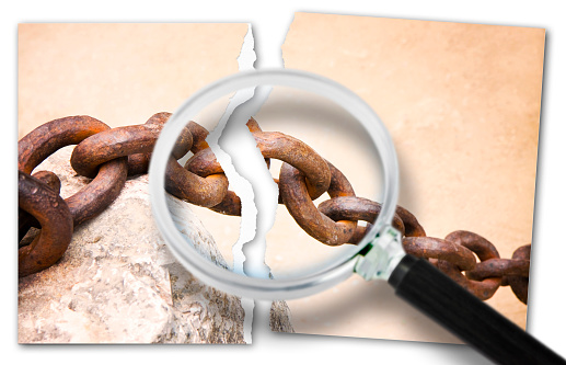Look for the reasons for relationship break-ups - breaking the chains - Focus concept image with a ripped photo of an old rusty metal chain seen through a magnifying glass.