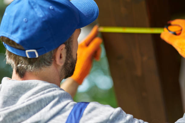 istock Close up of young workman wearing blue cap and overalls using measuring tape while working on cottage construction on a sunny day 1287808472