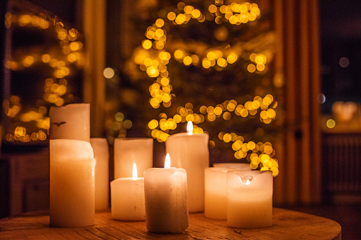 Still life with burning green candle in candle in rustic metal pot. Outdoor Christmas or winter garden decoration concept. Selective focus.