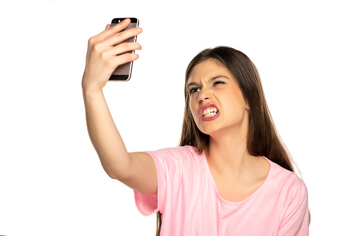Woman taking selfies and make funny faces on white background