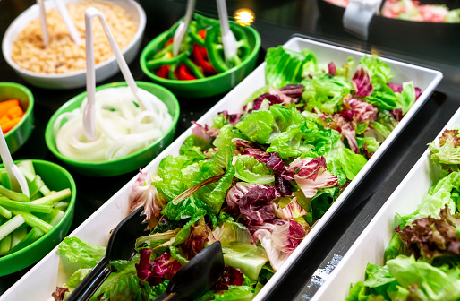 Salad bar buffet at restaurant. Fresh salad bar buffet for lunch or dinner. Healthy food. Fresh green and purple lettuce in white plate on counter. Catering food. Banquet service. Vegetarian food.