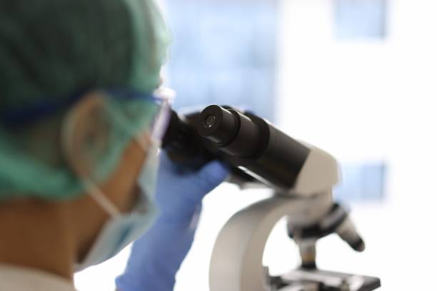 istock Medical research scientist looks through a microscope. 1287817945