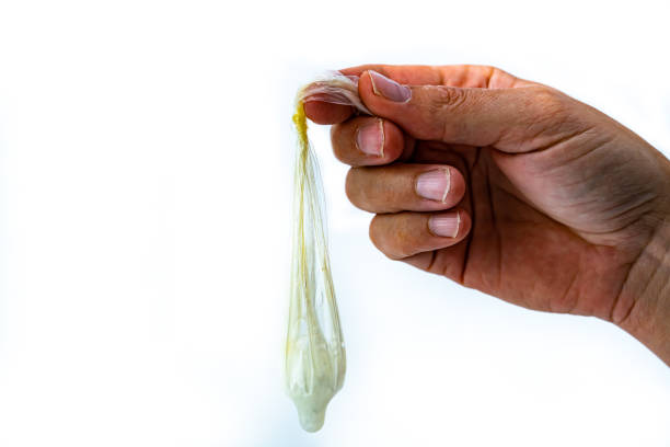 남성 손 은 내부에 정액과 함께 사용 된 콘돔을 들고, 콘돔에 매듭. 흰색으로 격리됩니다. - condom sex sexually transmitted disease aids 뉴스 사진 이미지