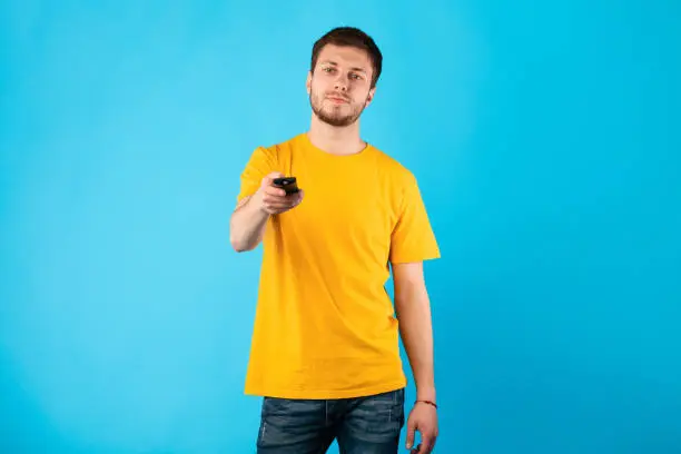 Photo of Man holding remote control isolated on blue background