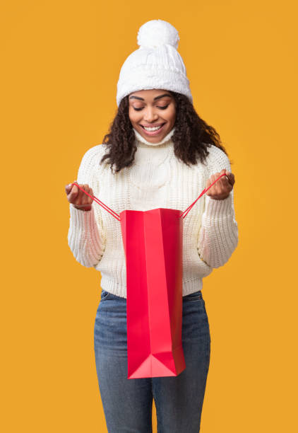 istock Young black lady holding shopping bag looking inside 1287822809