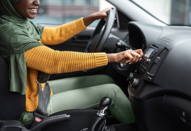 Unrecognizable black muslim woman turning on volume in car audio system Unrecognizable black muslim woman turning on volume in car audio system, enjoying listening music while driving in the city, african islamic lady testing her new automobile, cropped image, side view car audio equipment stock pictures, royalty-free photos & images