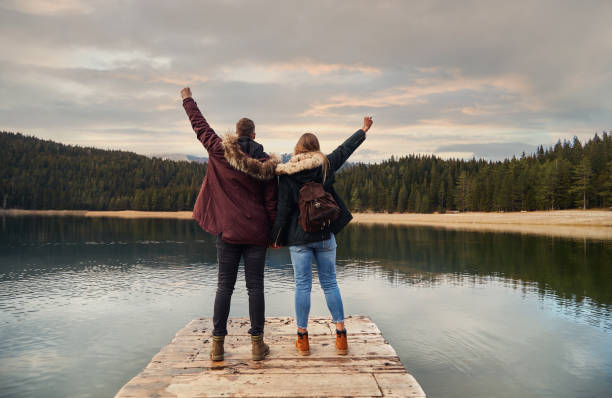 istock Couple Standing On Pier On Mountain Lake 1287825644