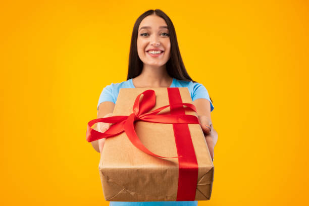 istock Happy woman holding gift box at studio, giving to camera 1287826228