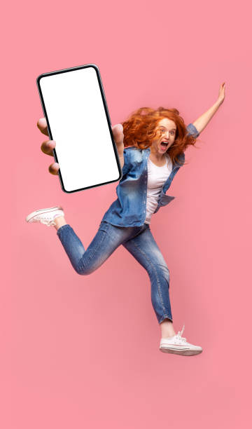 istock Positive redhead girl jumping over pink studio background 1287828918