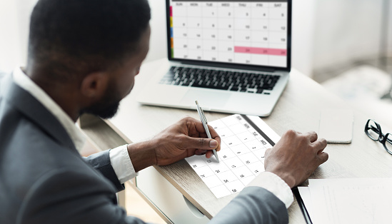 Planning Concept. Black Businessman Using Calendar Program On Laptop And Writing Notes To Planner, Managing His Business Schedule, Checking Events In Organizer, Creative Collage