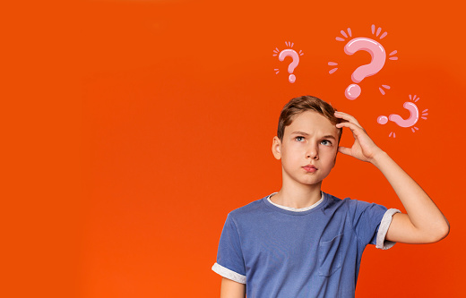 Thoughtful Caucasian teenager searching for creative solution to problem on orange background, collage with question marks. Copy space. Smart ideas and innovative decisions concept