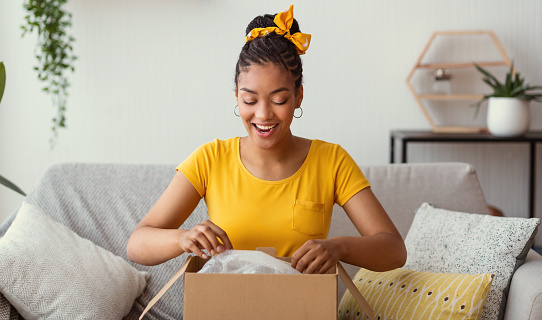 Feliz mujer negra desempaquetar caja después de las compras en línea photo