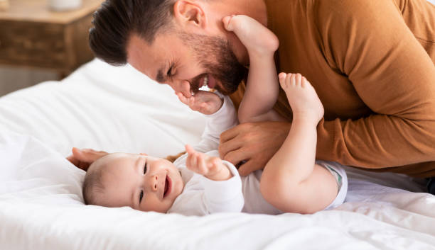 istock Father Cuddling Bonding With Little Baby Lying On Bed Indoor 1287833138