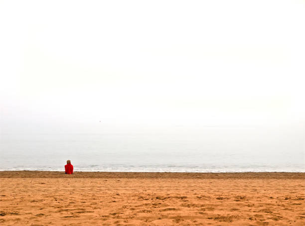 Woman with red coat on a lonely beach due to the confinement in Torremolinos