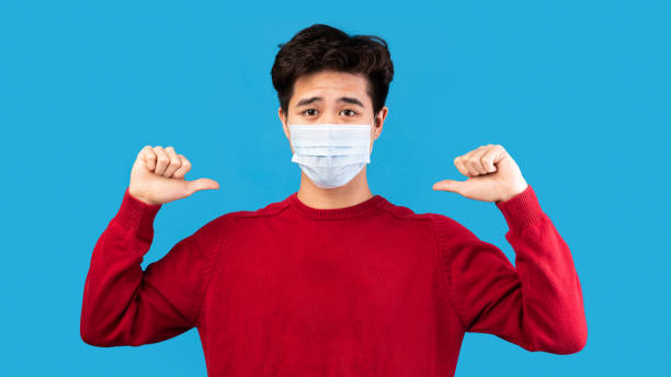 istock Asian guy in medical mask pointing at himself 1287833716