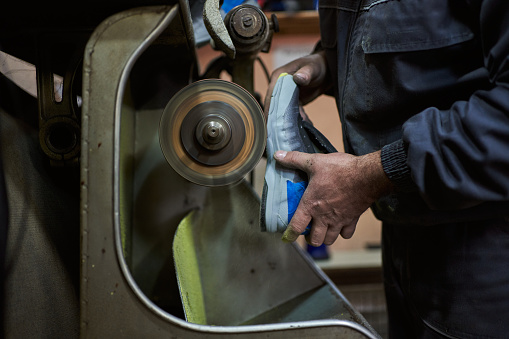 Mid adult cobbler hand repairing shoes in his messy workshop, while working on a ring binder