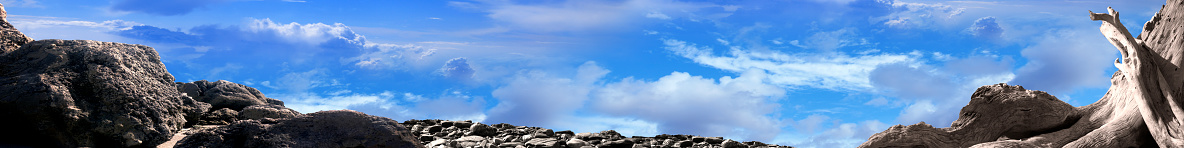 Conceptual empty dried rocky landscape over blue cloudy sky
