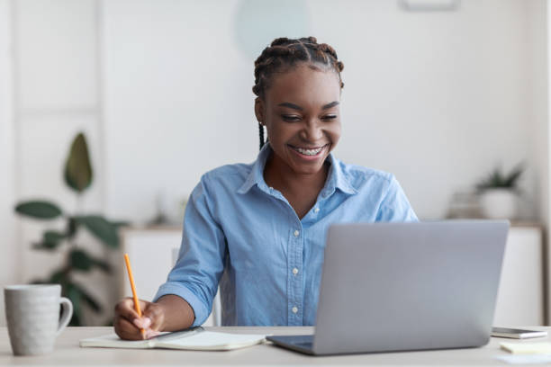 istock Online Education. Young Black Female Student Using Laptop At Home, Taking Notes 1287833810