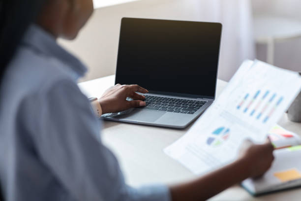 istock Black Female Employee Using Laptop With Black Screen And Working With Documents 1287833876