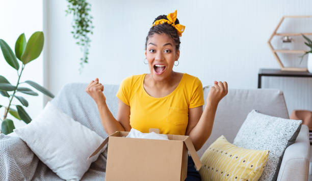 istock Excited black lady unpacking parcel after online shopping 1287836189