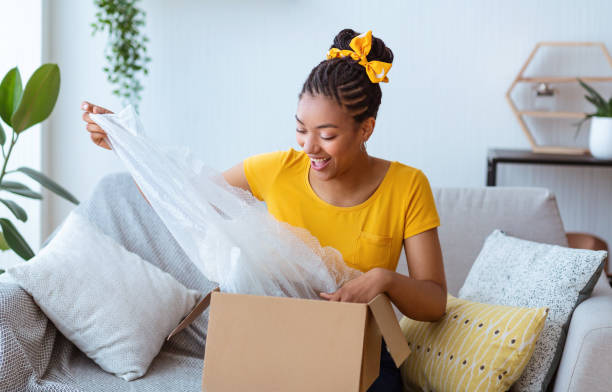 istock Happy black lady unpacking box after online shopping 1287836371