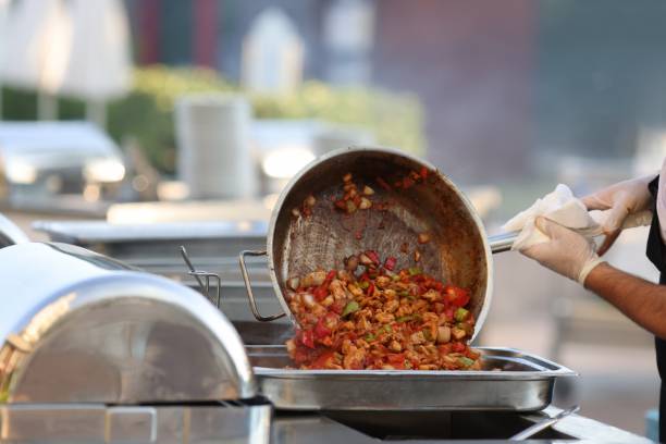 istock Man put cooked food from frying pan into metal container. 1287838796