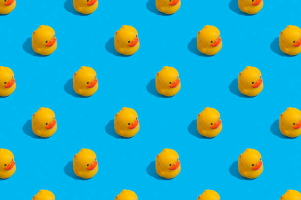 istock Seamless regular pattern with yellow ducks on a blue background. The concept of games in the bathroom and summer vacation. 1287839023