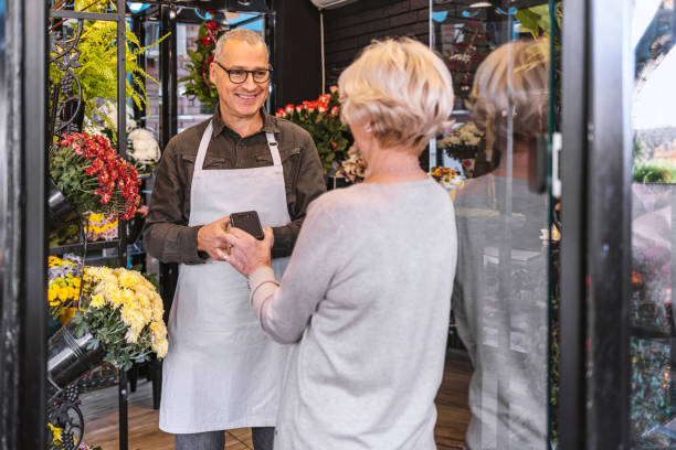 フラワーショップで非接触カードとnfc技術を通じて支払う - florist supermarket flower bouquet ストックフォトと画像