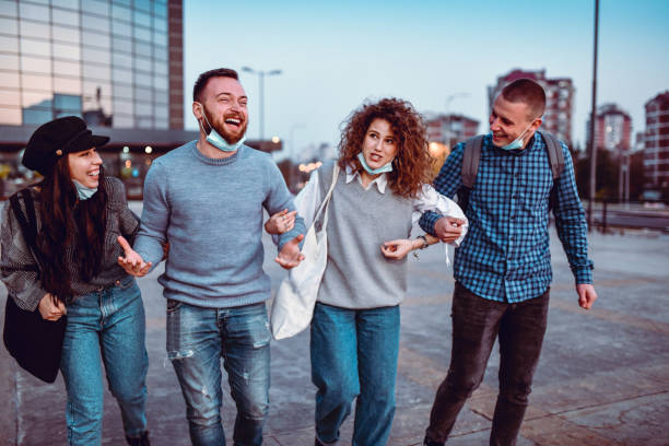 istock Irresponsible Friends Taking Off Protective Masks And Walking While Holding Hands 1287839243