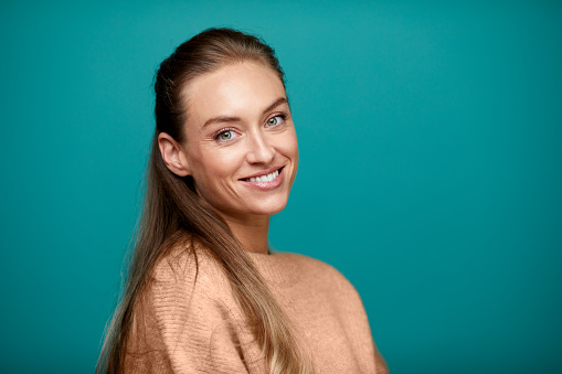 Studio shot of a young woman looking at the camera.\nOne cute woman wearing a sweater and looking at the camera.