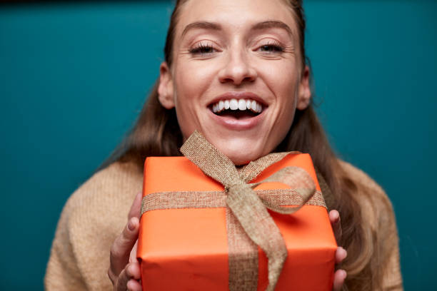 istock One woman happily hugging a Christmas gift. 1287842908