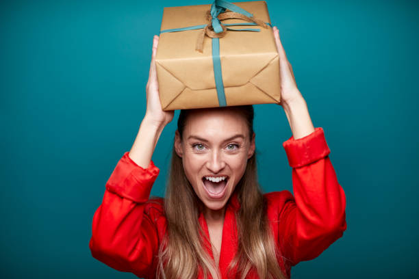 Excited woman holding a gift above her head.