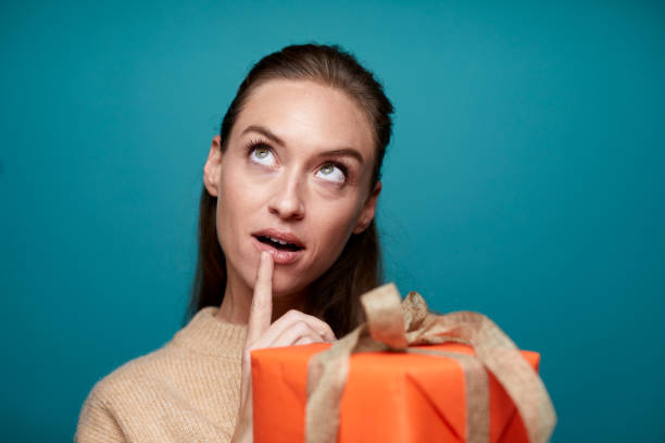 istock Woman holding a Christmas gift and looking upwards. 1287843411