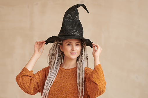 Happy Halloween! Happy young woman in halloween witch costume with broom on a light background. Halloween party concept.