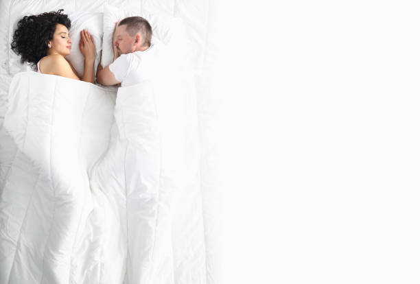 man and woman on white bed lie with their eyes closed. - bedroom authority indoors home interior imagens e fotografias de stock