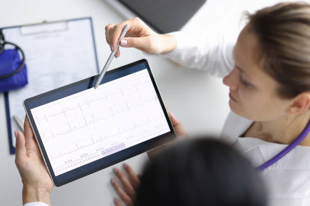 ärzte kardiologen, die kardiogramm auf tablette betrachten und es mit stift zeigen - human heart surveillance computer monitor pulse trace stock-fotos und bilder