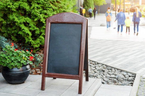 istock Signboard on the street. Empty menu board stand. Restaurant sidewalk chalkboard sign board. Freestanding A-frame blackboard near outdoor cafe. Copyspace for text, selective focus 1287857255