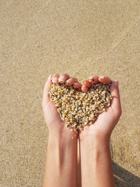 istock Mellow heart shaping female hands above sea and beach 1287857727