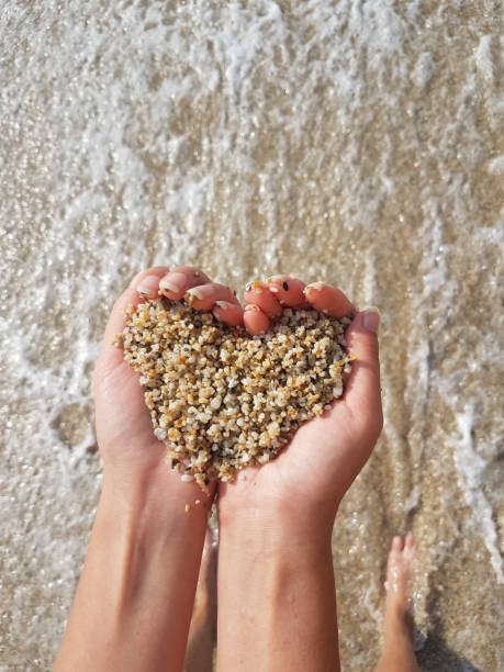 istock Mellow heart shaping female hands above sea and beach 1287857731